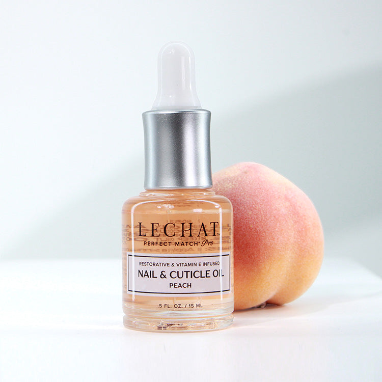 Bottle of LeChat nail and cuticle oil with a peach on a white background