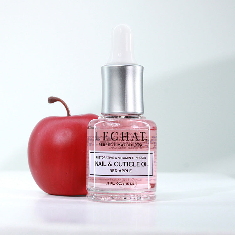 Bottle of LeChat nail and cuticle oil with a red apple on a white background